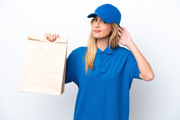 Young Uruguayan woman taking a bag of takeaway food isolated on white background having doubts