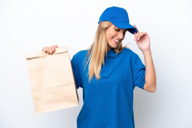 Young Uruguayan woman taking a bag of takeaway food isolated on white background laughing