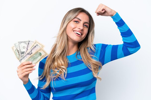 Young Uruguayan woman taking a lot of money isolated on white background doing strong gesture