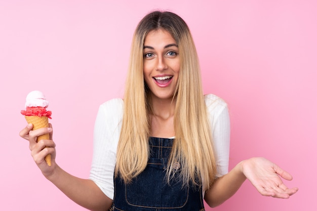 Young Uruguayan woman with a cornet ice cream over isolated pink wall with shocked facial expression