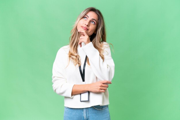 Young Uruguayan woman with ID card over isolated background having doubts while looking up