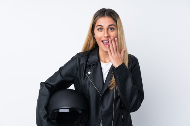 Молодая уругвайская женщина с мотоциклетным шлемом над изолированной белой стеной с удивленным выражением лица