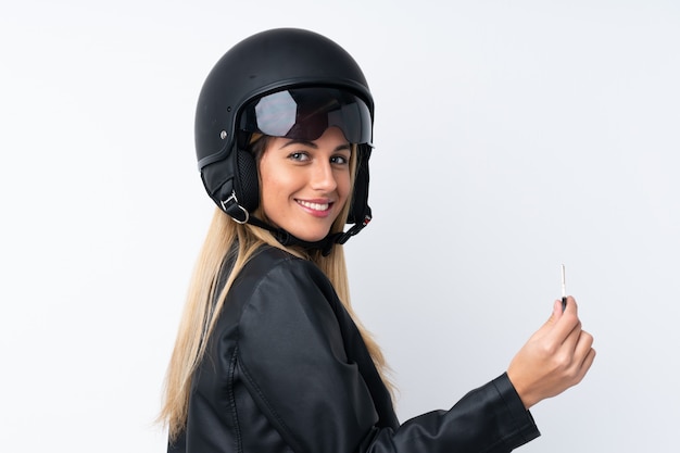 Young Uruguayan woman with a motorcycle helmet over isolated white wall