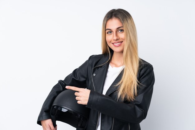 Young Uruguayan woman with a motorcycle helmet pointing finger to the side