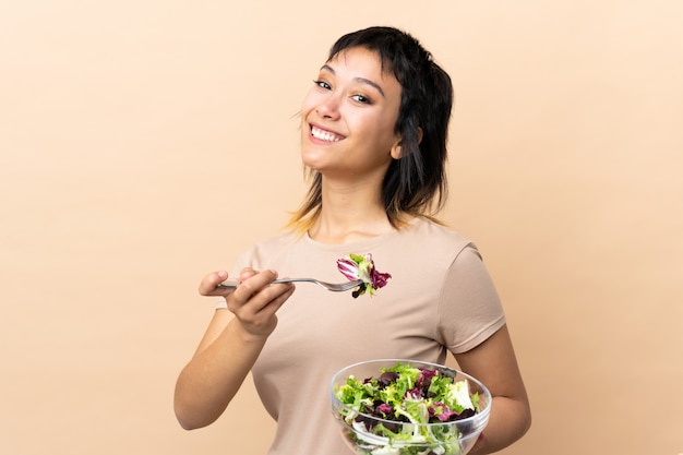 Young Uruguayan woman with salad over wall