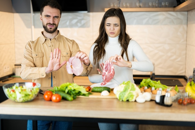 Young vegetarian couple is showing that it's wrong to eat meat and prefer fresh vegetables