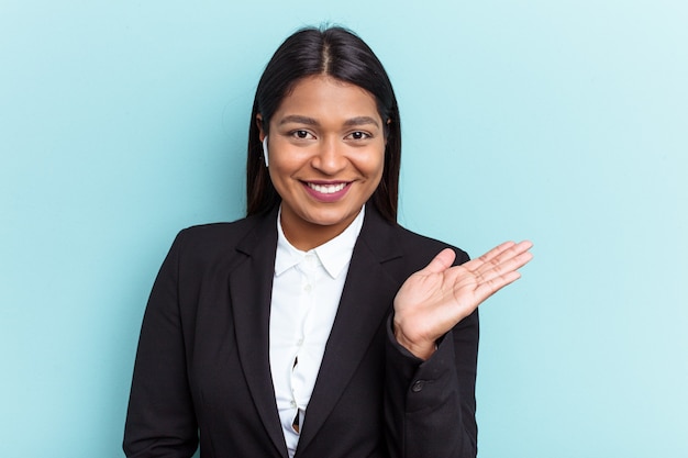 Young Venezuelan business woman isolated on blue background showing a copy space on a palm and holding another hand on waist.