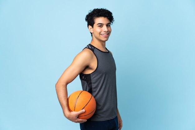 Young Venezuelan man isolated on blue wall playing basketball