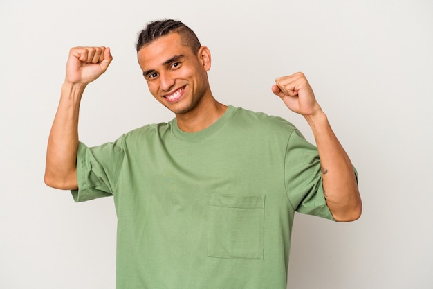 Young venezuelan man isolated on white background celebrating a special day, jumps and raise arms with energy.