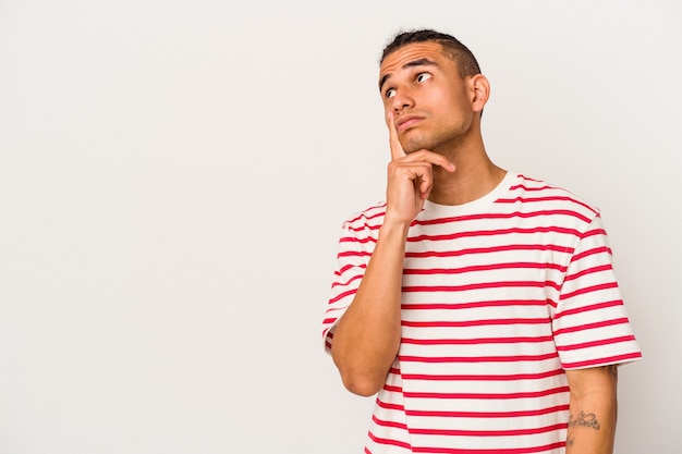 Young venezuelan man isolated on white background looking sideways with doubtful and skeptical expression.