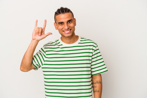 Young venezuelan man isolated on white background showing a horns gesture as a revolution concept.