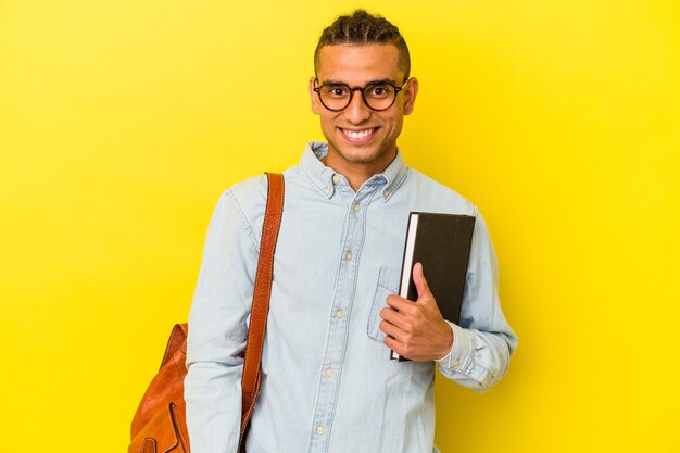 Молодой венесуэльский студент человек изолирован на желтом фоне счастливым, улыбающимся и веселым.