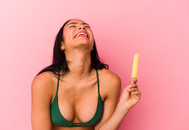 Young Venezuelan woman holding an ice cream isolated on pink background