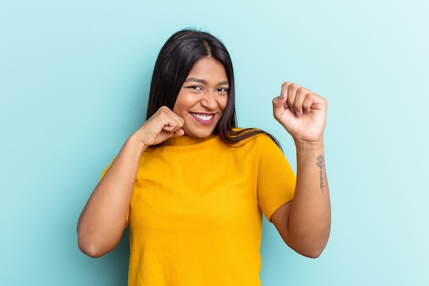 Young Venezuelan woman isolated on blue background dancing and having fun.