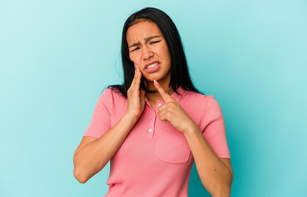 Young Venezuelan woman isolated on blue background having a strong teeth pain molar ache