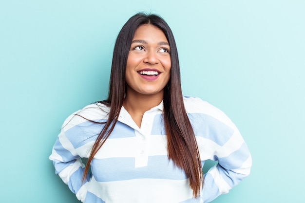 Young Venezuelan woman isolated on blue background relaxed and happy laughing, neck stretched showing teeth.