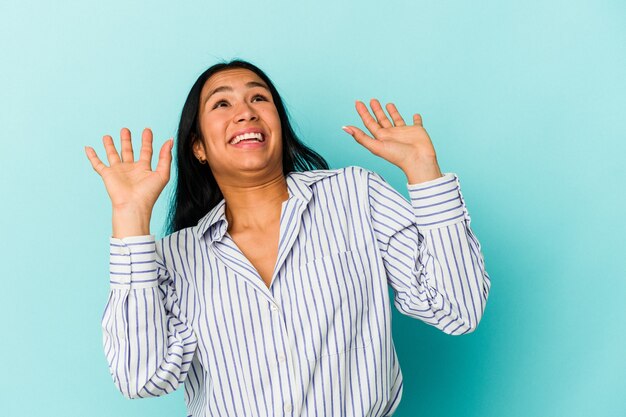 空に向かって叫び、見上げて、欲求不満の青い背景に孤立した若いベネズエラの女性。