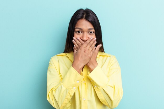 Young Venezuelan woman isolated on blue background shocked covering mouth with hands.