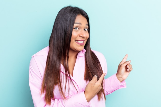 Young Venezuelan woman isolated on blue background shocked pointing with index fingers to a copy space.