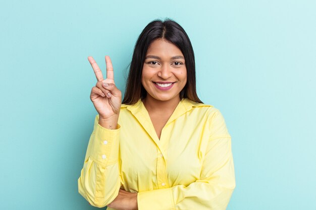 Young Venezuelan woman isolated on blue background showing number two with fingers.