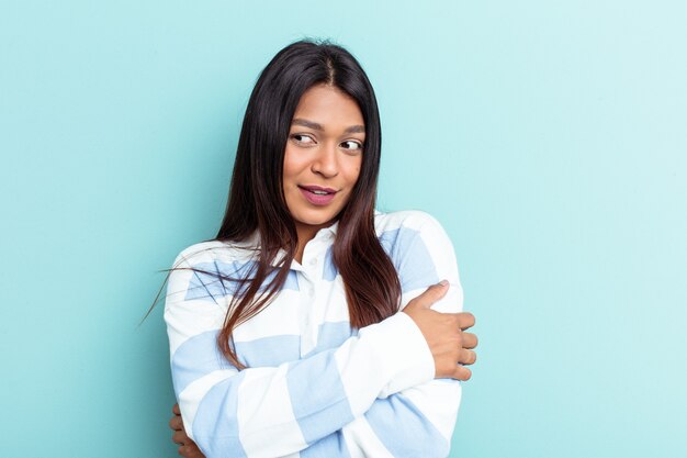 Young Venezuelan woman isolated on blue background smiling confident with crossed arms.