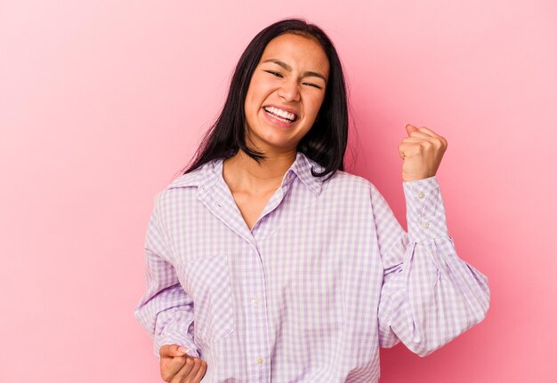 Young Venezuelan woman isolated on pink background cheering carefree and excited Victory concept