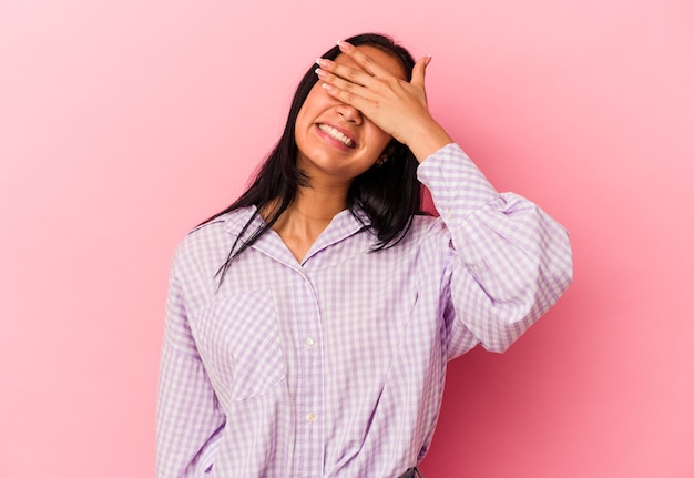 Young Venezuelan woman isolated on pink background covers eyes with hands, smiles broadly waiting for a surprise.