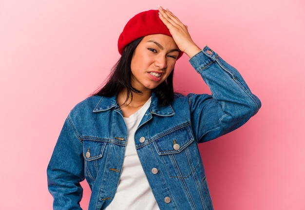 Young Venezuelan woman isolated on pink background forgetting something, slapping forehead with palm and closing eyes.