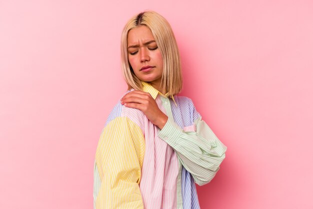 Young venezuelan woman isolated on pink background having a shoulder pain.