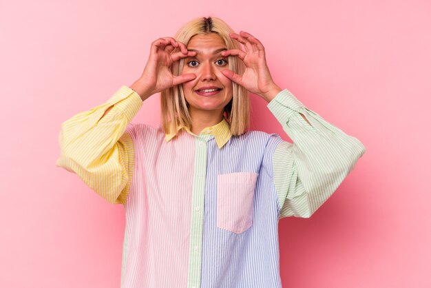 Young venezuelan woman isolated on pink background keeping eyes opened to find a success opportunity.