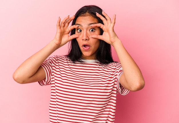 Young Venezuelan woman isolated on pink background keeping eyes opened to find a success opportunity