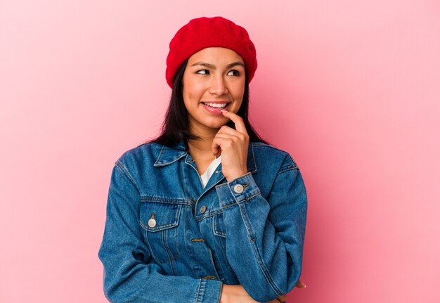 Young Venezuelan woman isolated on pink background relaxed thinking about something looking at a copy space.