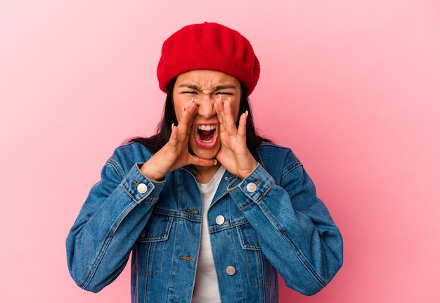 Young Venezuelan woman isolated on pink background shouting excited to front.