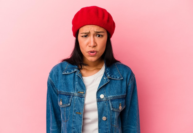 Young Venezuelan woman isolated on pink background shouting very angry rage concept frustrated