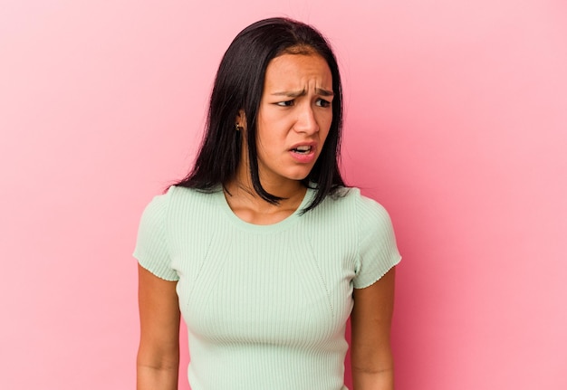 Young Venezuelan woman isolated on pink background shouting very angry rage concept frustrated