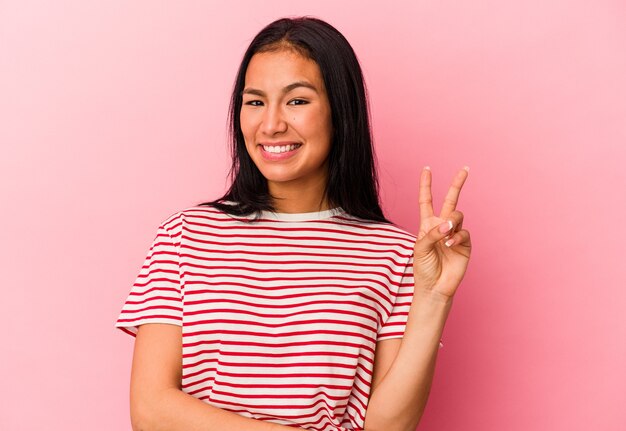 Young Venezuelan woman isolated on pink background showing number two with fingers.