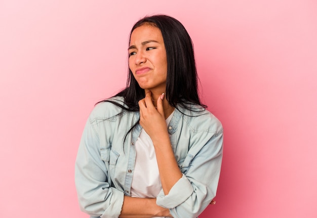 Young Venezuelan woman isolated on pink background suffers pain in throat due a virus or infection.