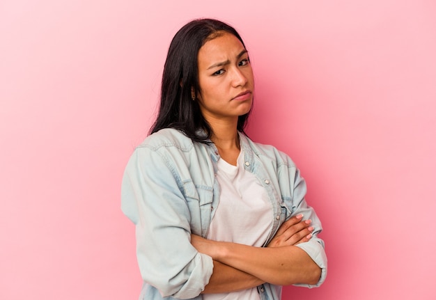 Young Venezuelan woman isolated on pink background suspicious, uncertain, examining you.