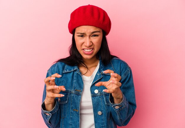 Young Venezuelan woman isolated on pink background upset screaming with tense hands.