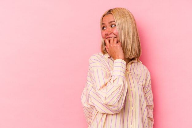 Young venezuelan woman isolated on pink wall relaxed thinking about something looking at a copy space.