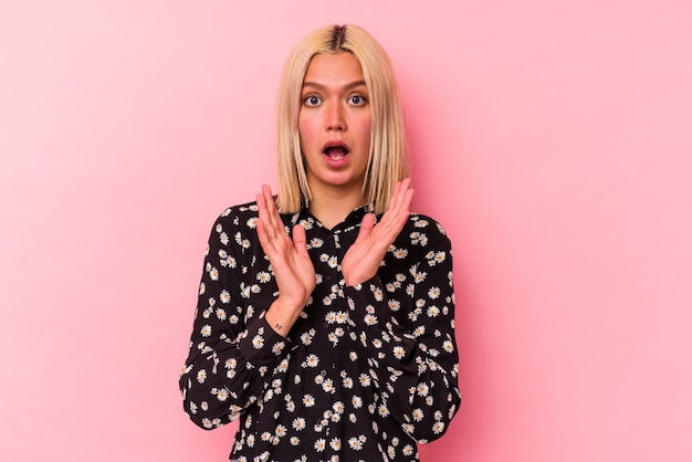 Young venezuelan woman isolated on pink wall surprised and shocked.