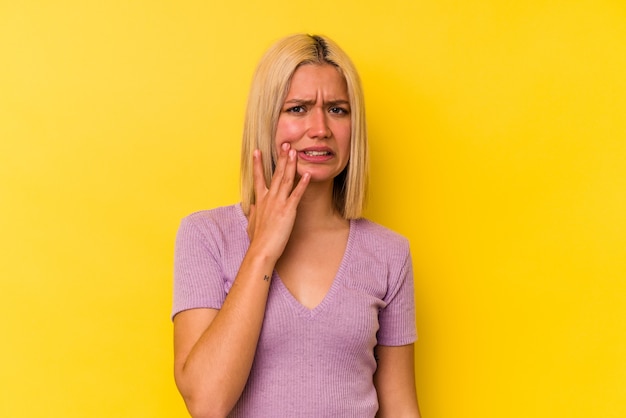 Young venezuelan woman isolated on yellow background having a strong teeth pain, molar ache.