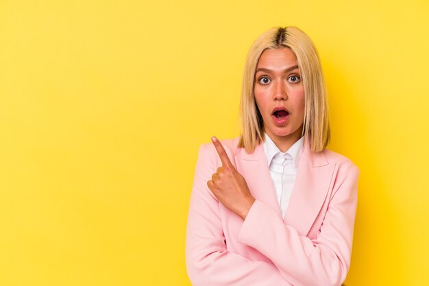 Young venezuelan woman isolated on yellow background pointing to the side