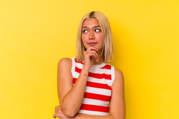 Young venezuelan woman isolated on yellow background thinking and looking up, being reflective, contemplating, having a fantasy.