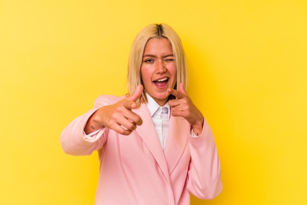 Young venezuelan woman isolated on yellow wall pointing to front with fingers.