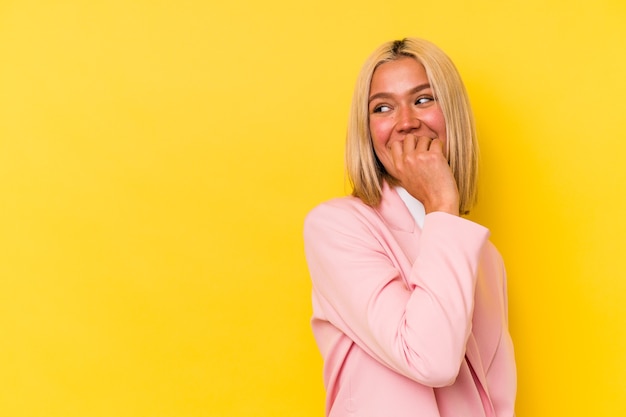 Young venezuelan woman isolated on yellow wall relaxed thinking about something looking at a copy space.