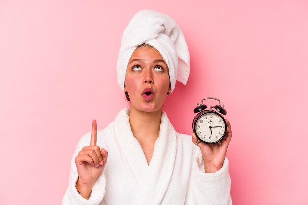 Young venezuelan woman late for work isolated on pink background pointing upside with opened mouth.