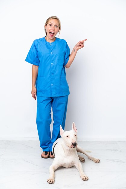 Young veterinarian English woman with dog isolated on white background surprised and pointing finger to the side