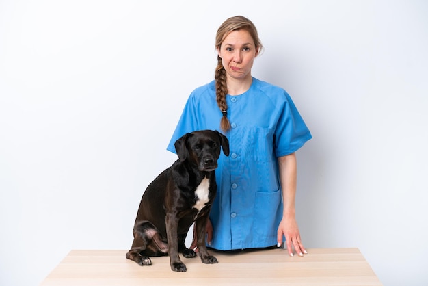 Young veterinarian woman with dog isolated on white background with sad expression