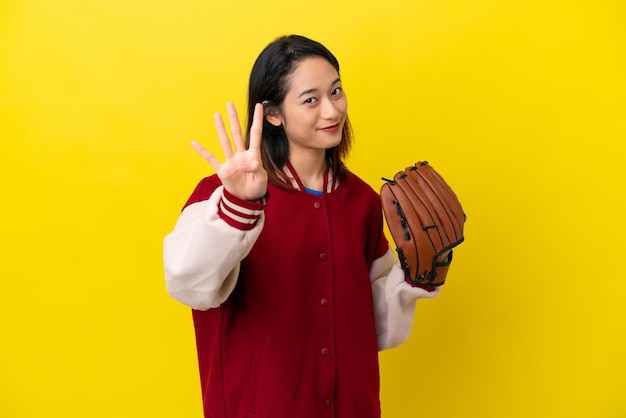 Young Vietnamese player woman with baseball glove isolated on yellow background happy and counting four with fingers